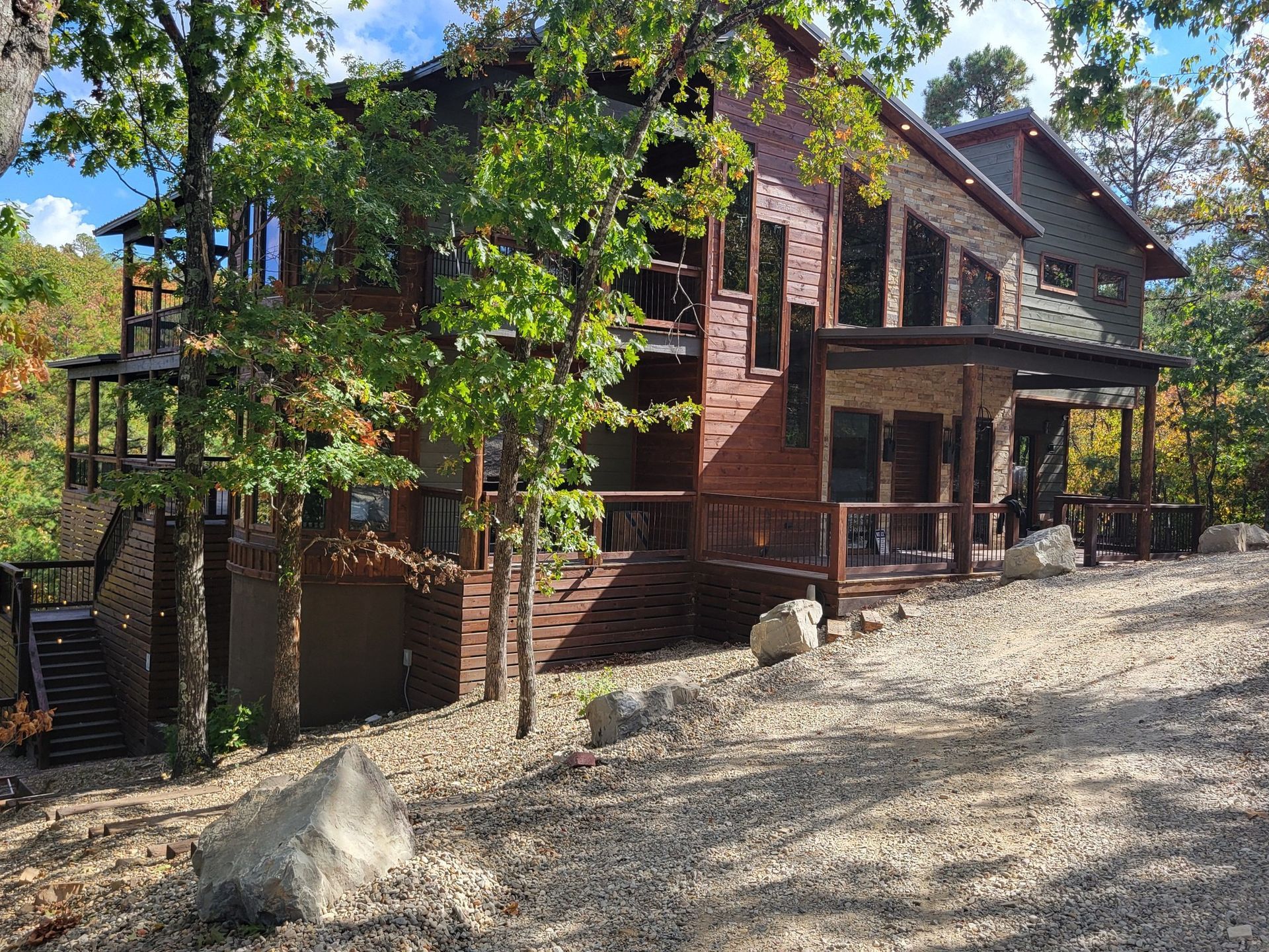 A large house with a lot of windows is surrounded by trees and gravel.