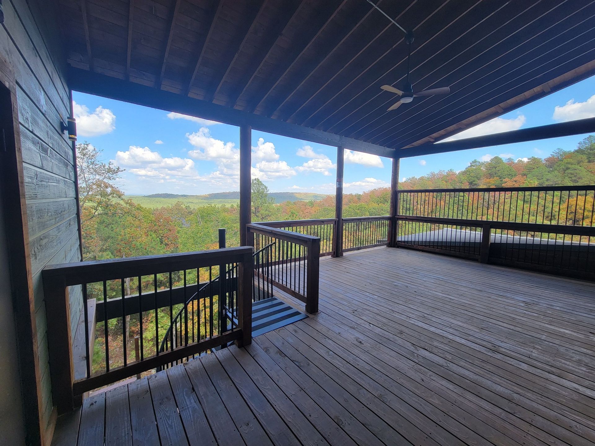 A large wooden deck with a view of a forest.