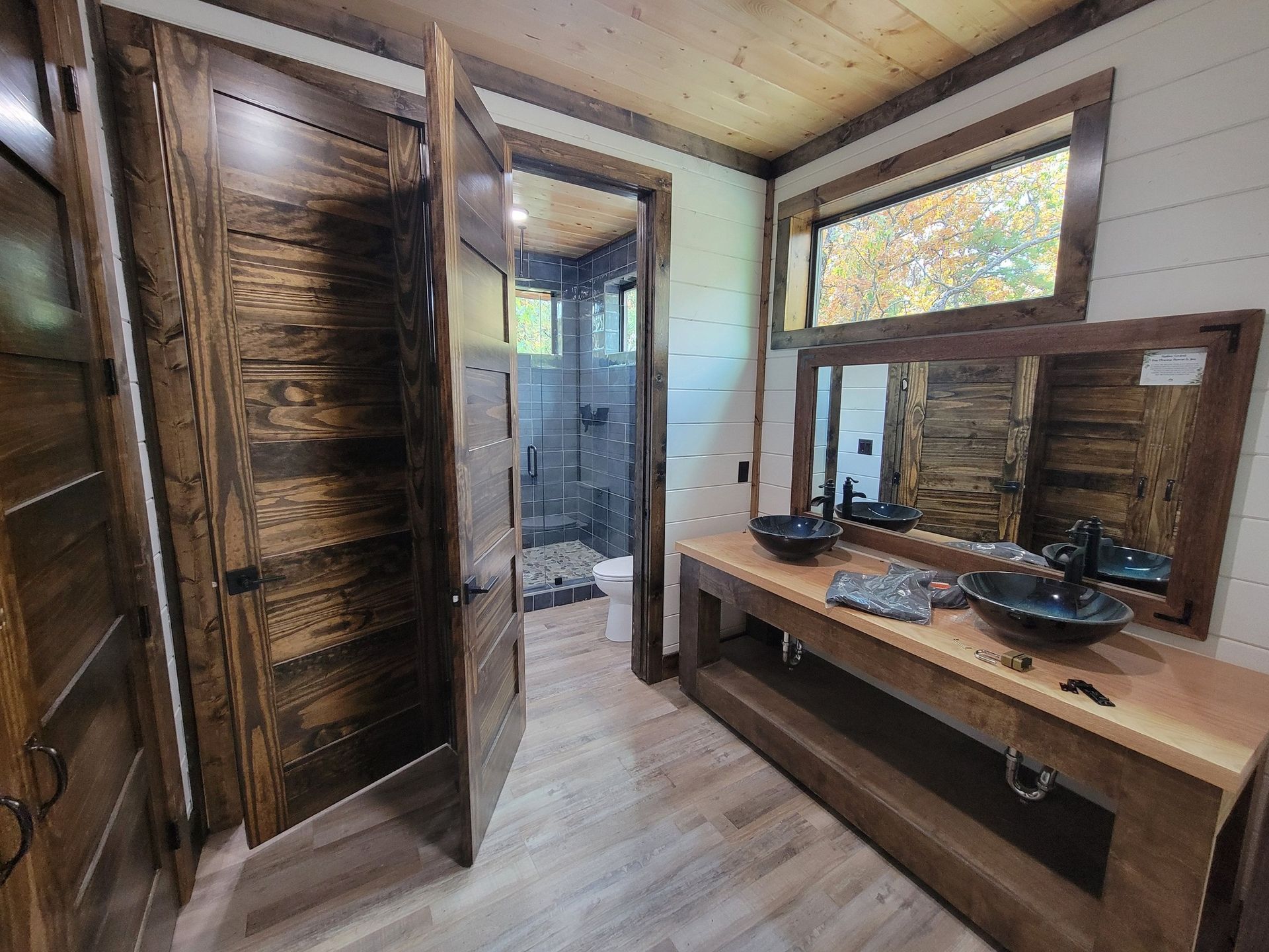 A bathroom with two sinks , a mirror and a walk in shower.