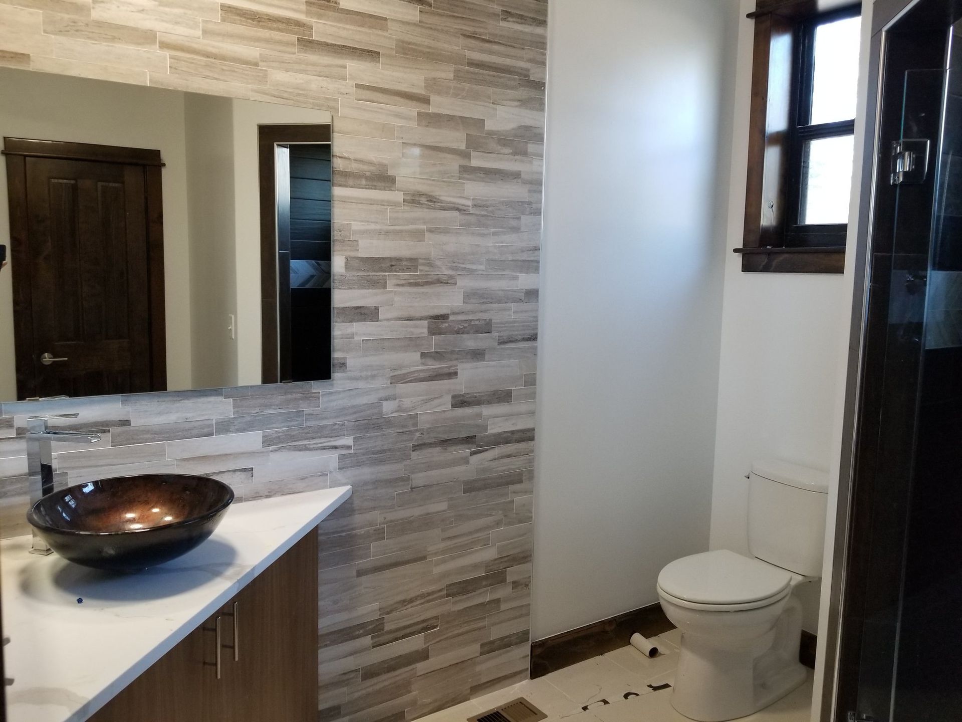 A bathroom with a toilet , sink and mirror.