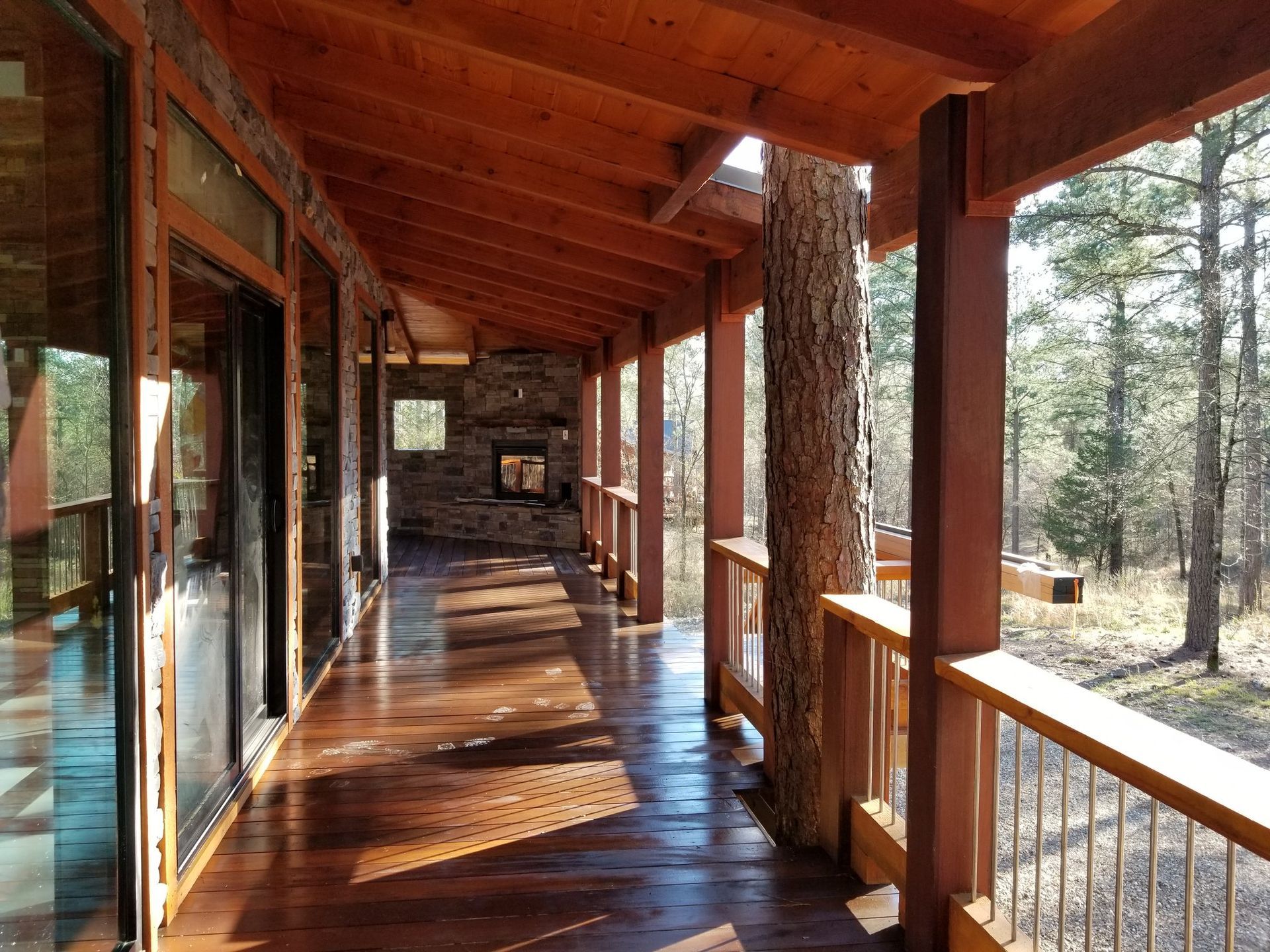 A long wooden porch with a fireplace in the background