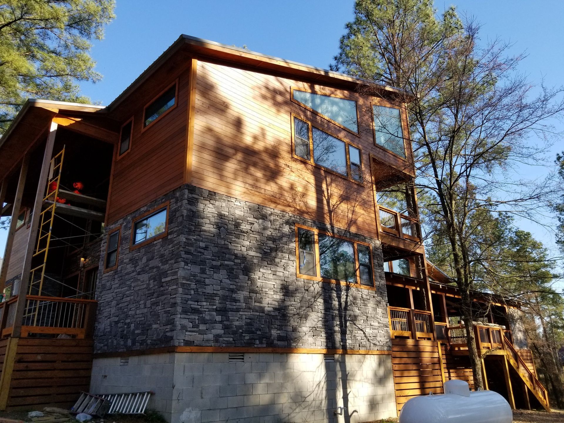 A large house with a lot of windows and a propane tank in front of it.