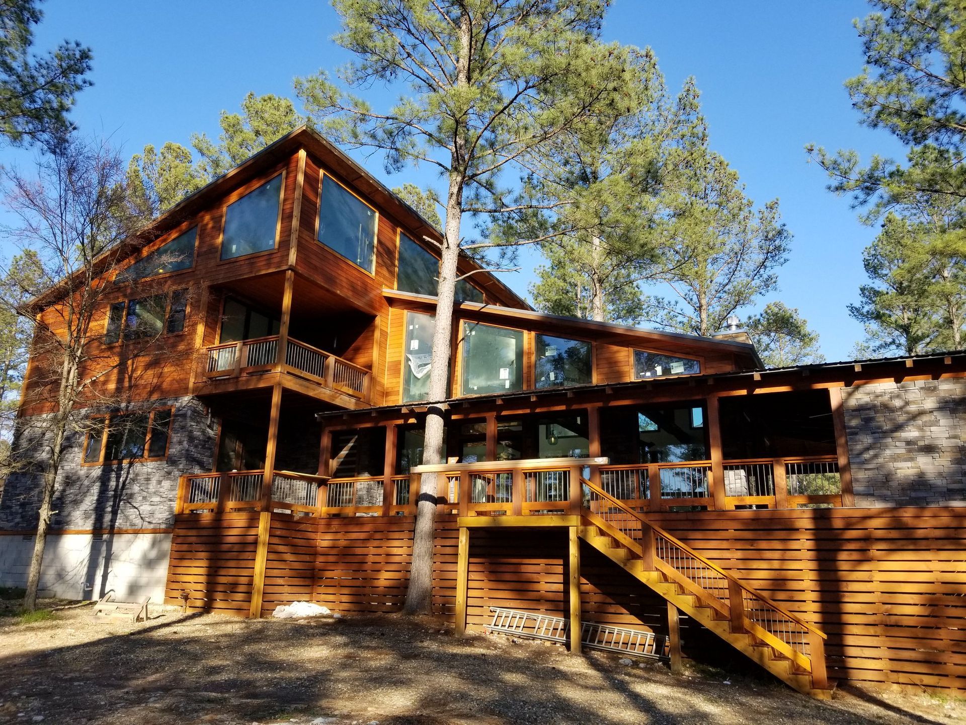 A large wooden house with a large deck in the middle of a forest.