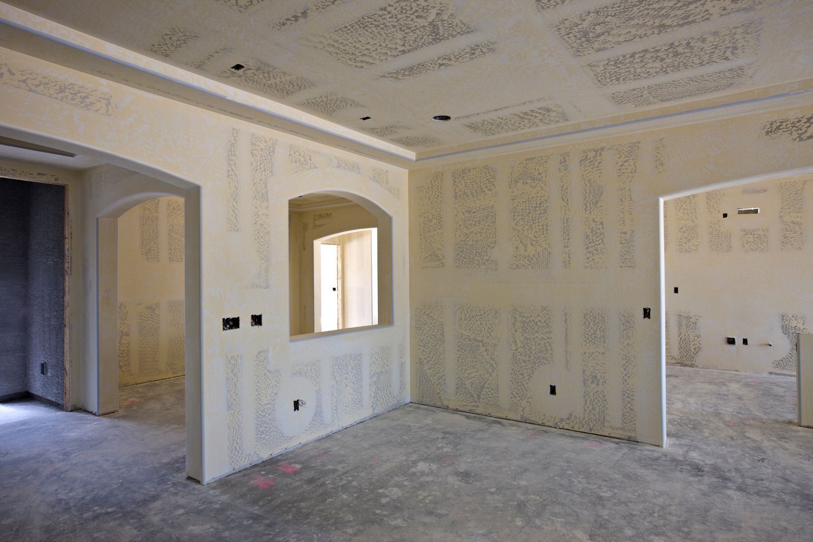 An empty room with drywall walls and a window in a house under construction.