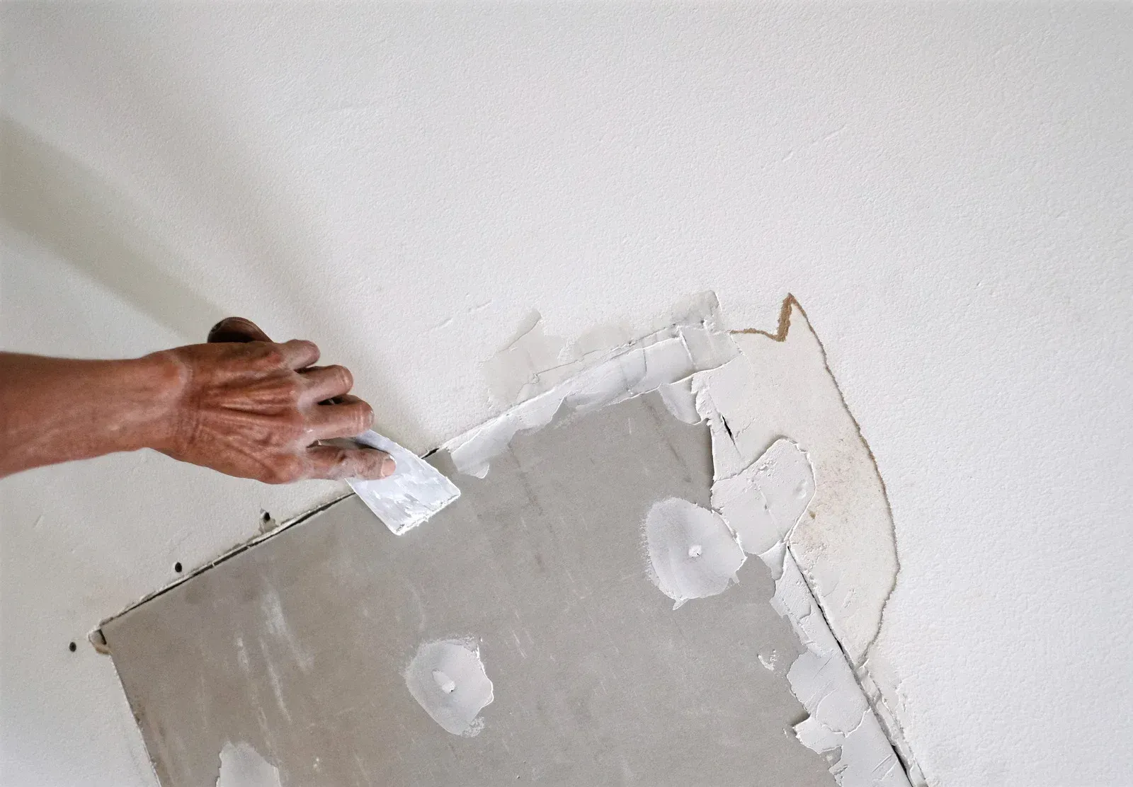 A person is plastering a wall with a spatula.