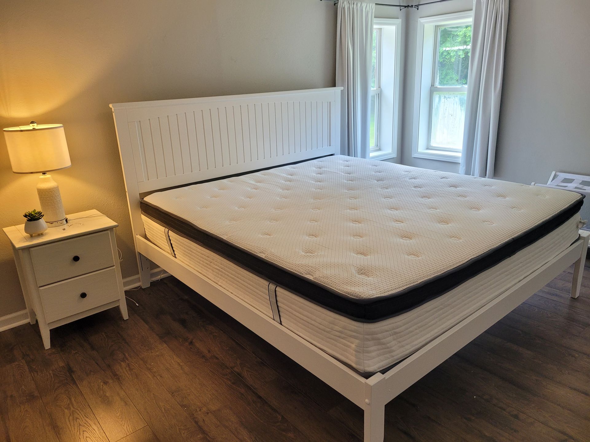 A bed with a mattress and a nightstand in a bedroom.