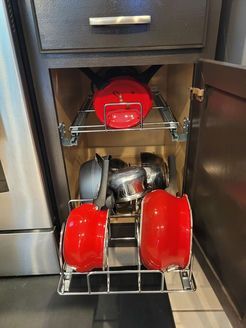 A kitchen cabinet with pots and pans in it.