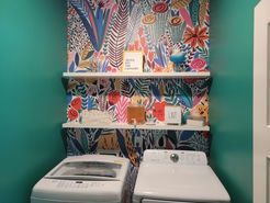 A laundry room with a washer and dryer and shelves.