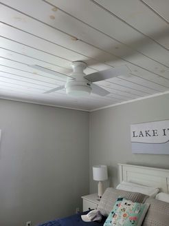 A bedroom with a ceiling fan and a bed.