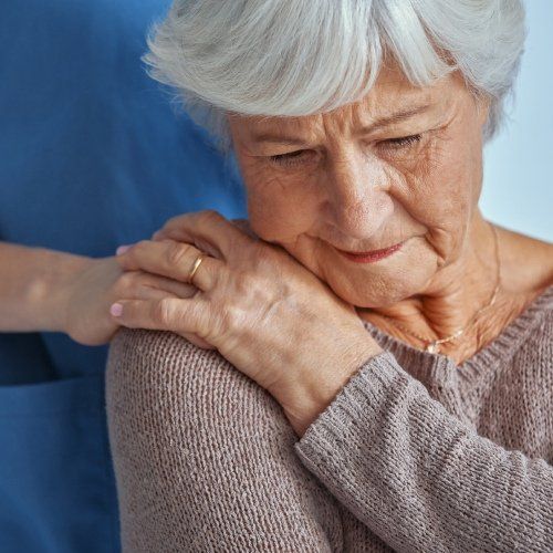 Mano appoggiata su una spalla di un'anziana