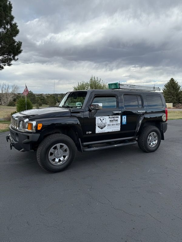 Black SUV with off-road gear and company decals parked on a road under cloudy skies