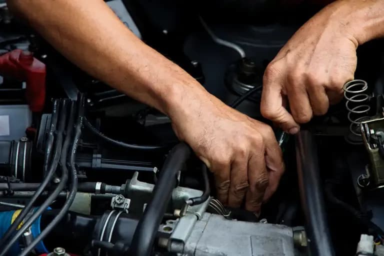 A Man is Working on a Car Engine With a Wrench — Port Macquarie Automotive Specialists in Port Macquarie, NSW