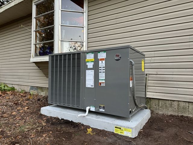 Outdoor HVAC unit beside a house exterior wall on a concrete pad