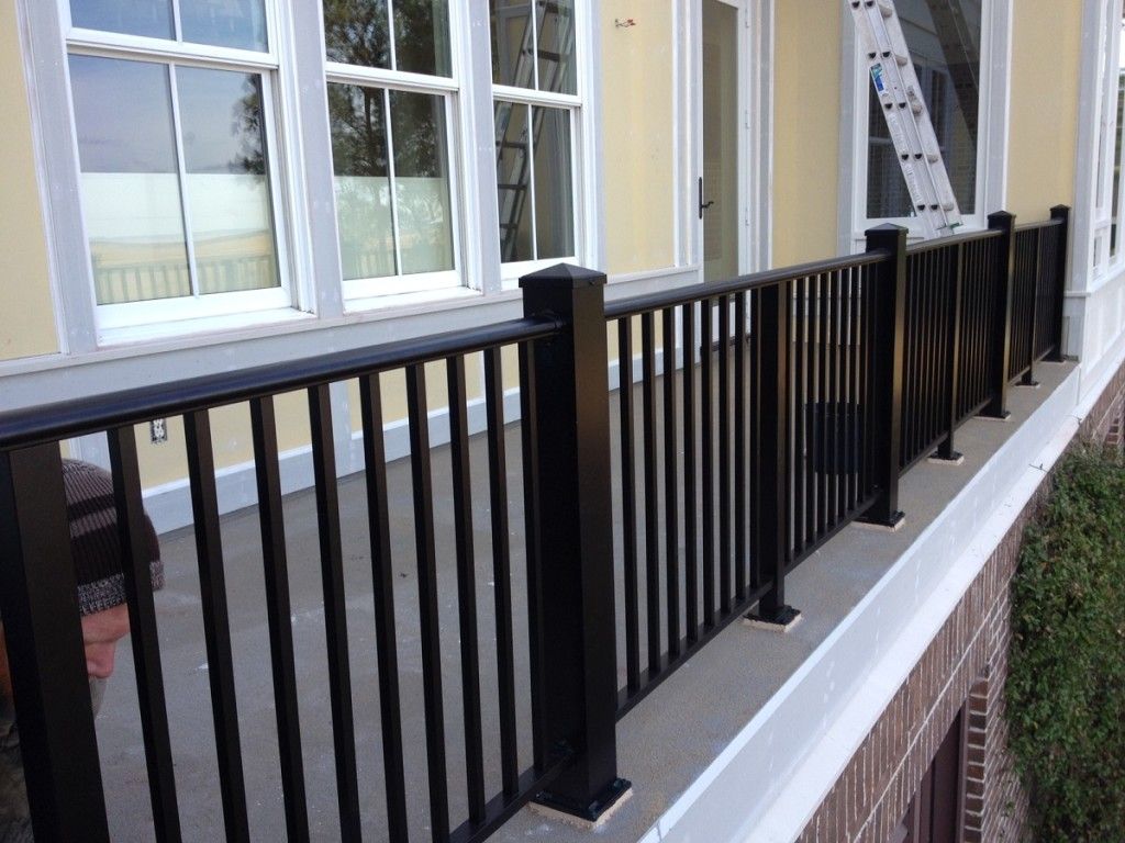 There is a black railing on the side of a house.