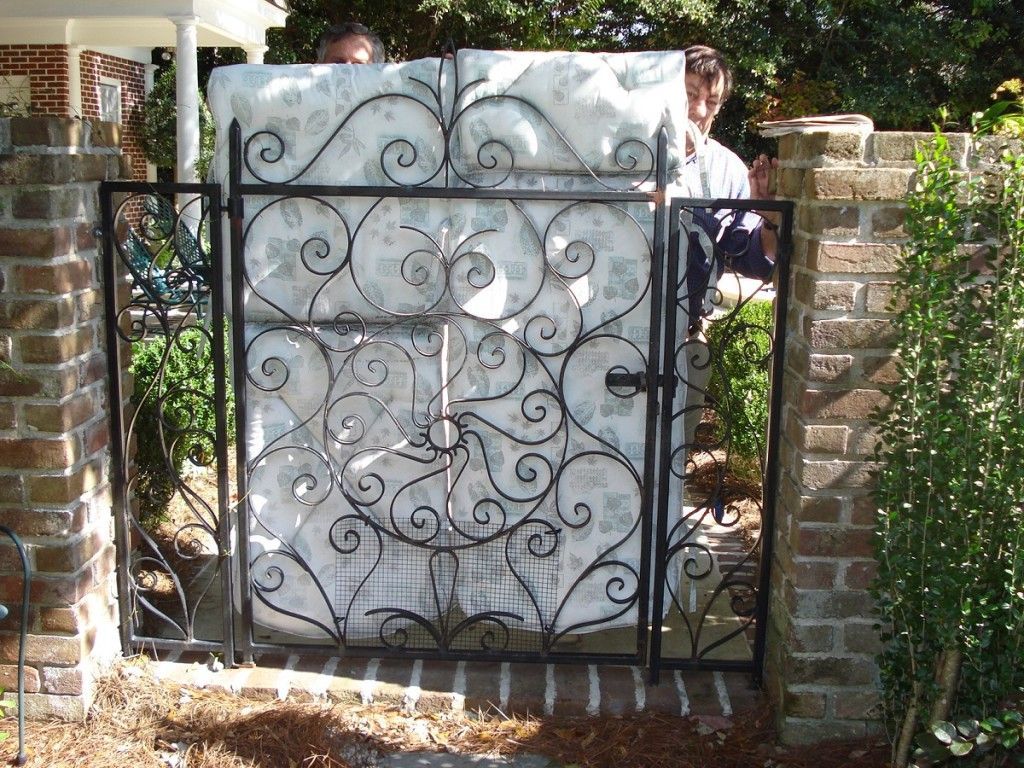 A wrought iron gate with a mattress behind it