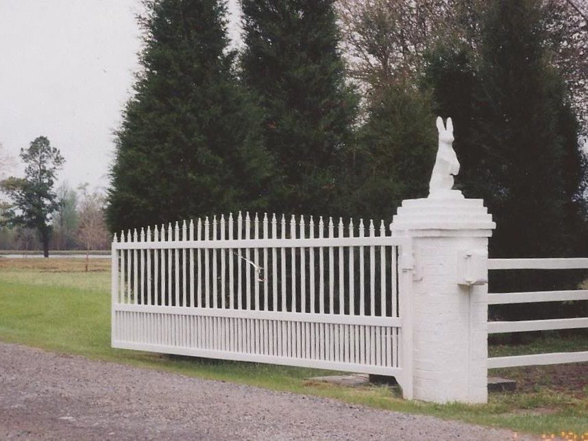 A white fence with a statue of a rabbit on top of it