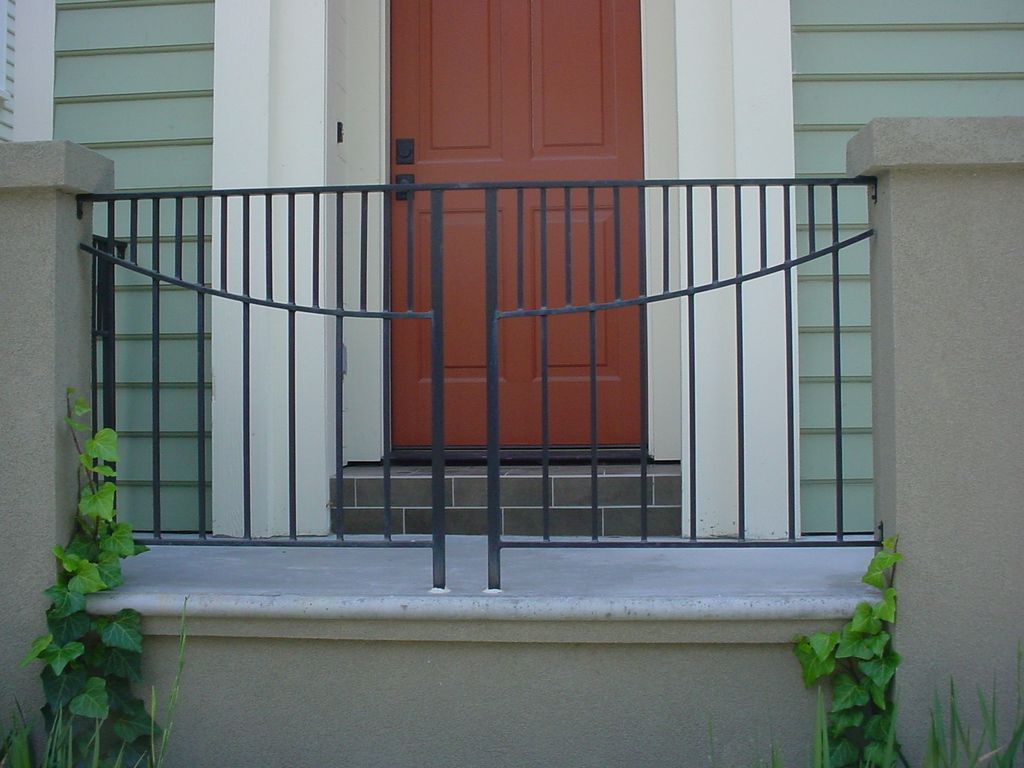 A red door is behind a wrought iron fence