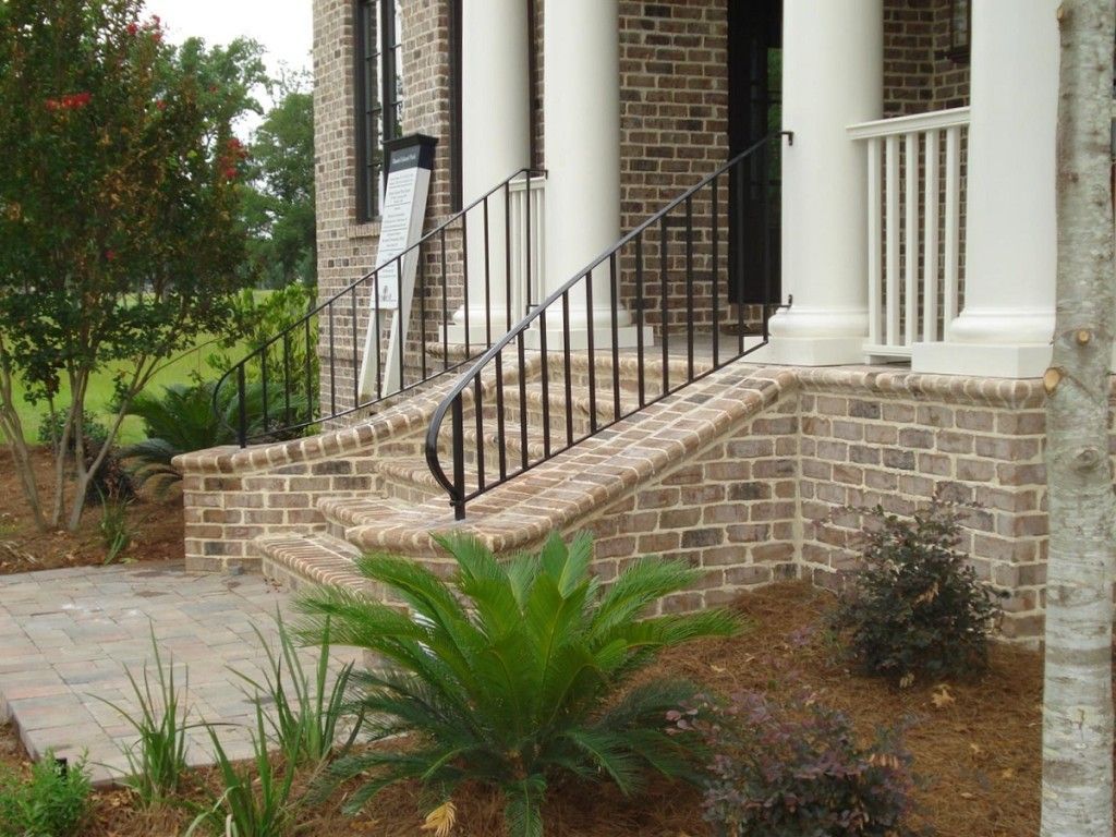 A brick house with stairs and a wrought iron railing