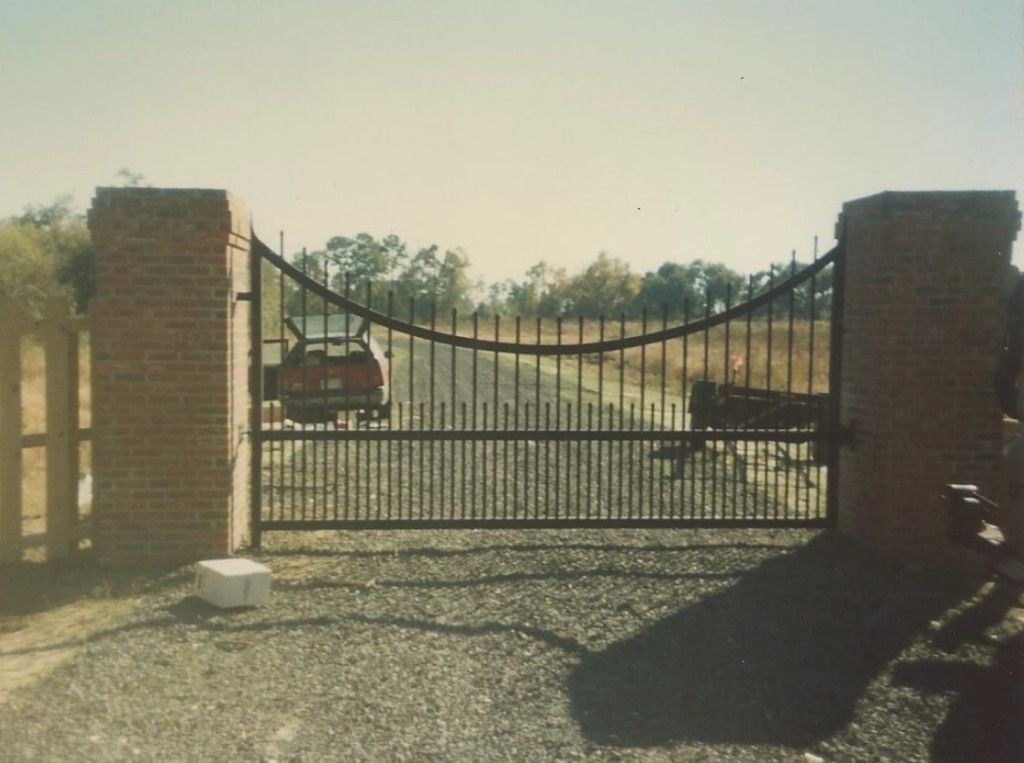 A car is parked behind a gate that is open