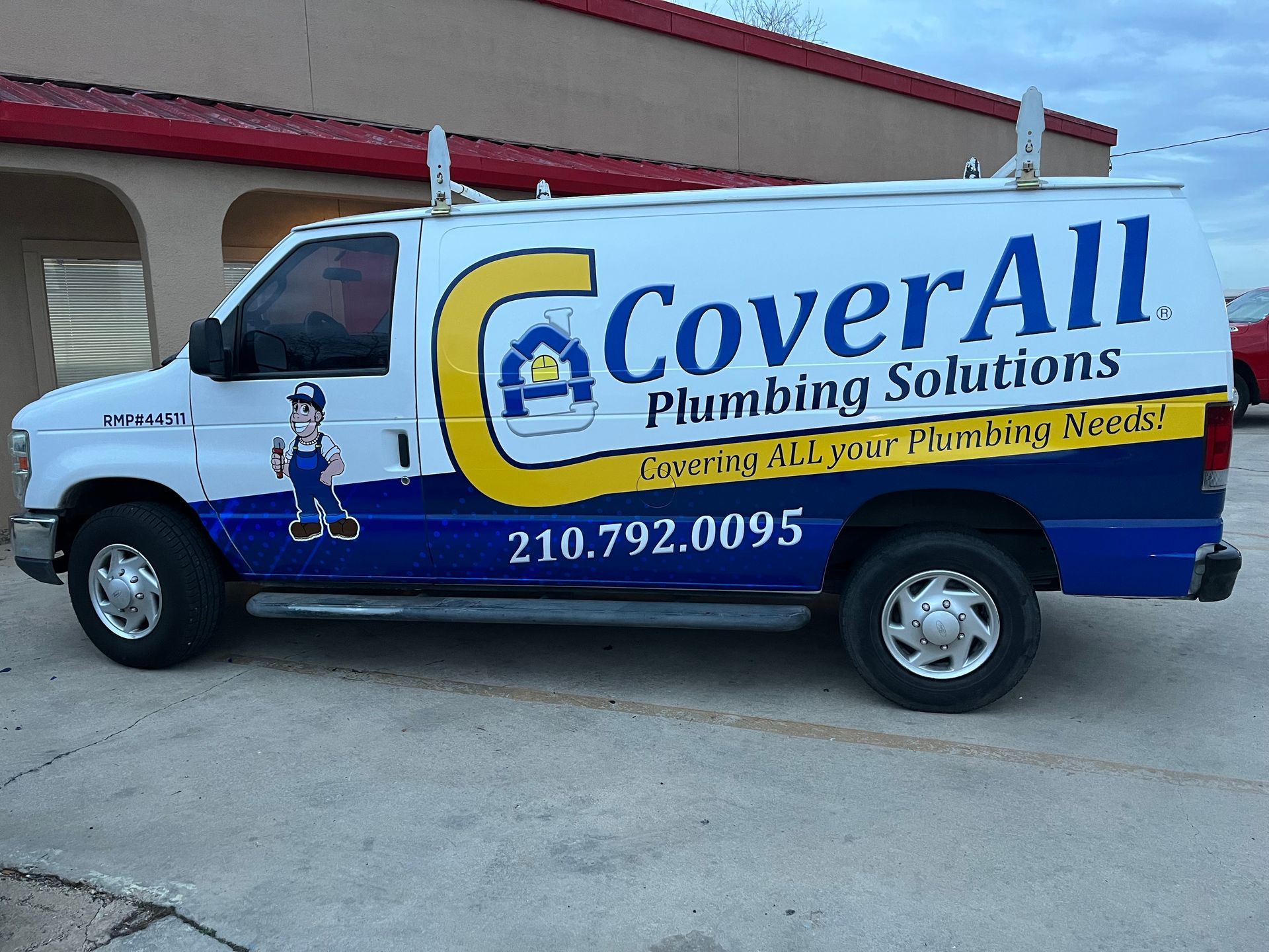 A cover all plumbing solutions van is parked in front of a building