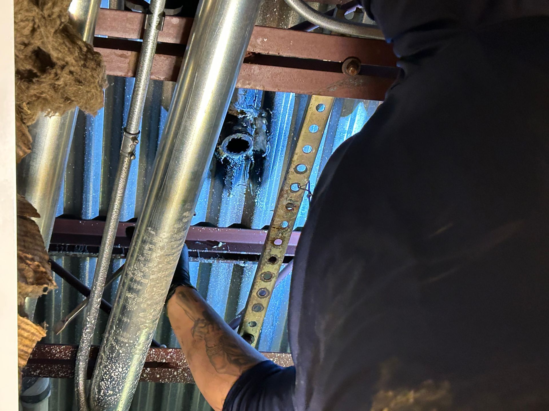 A man is working on a pipe in a building.