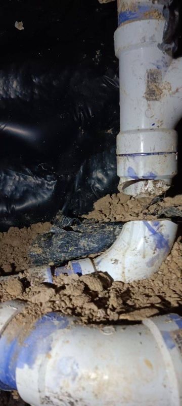 A bunch of white pipes are laying in the dirt.