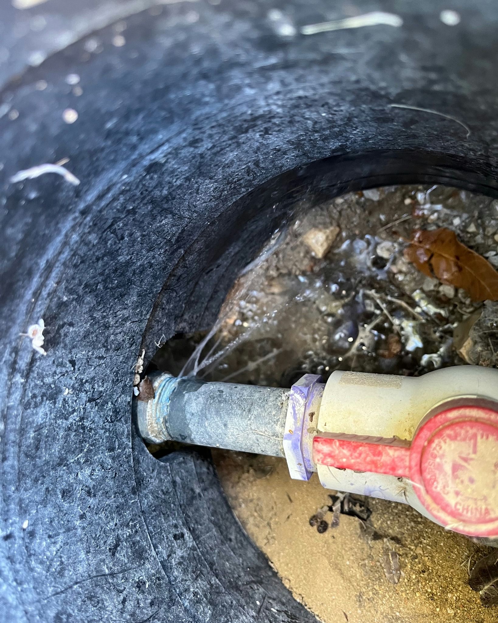 A close up of a water valve in a hole in the ground.