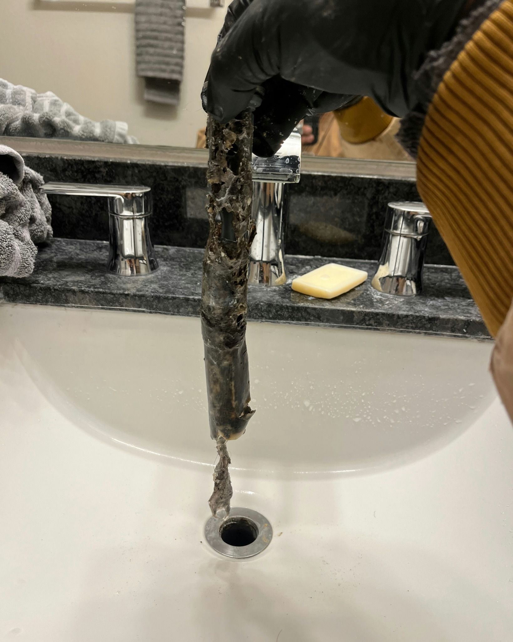 A person is cleaning a sink with a hose.