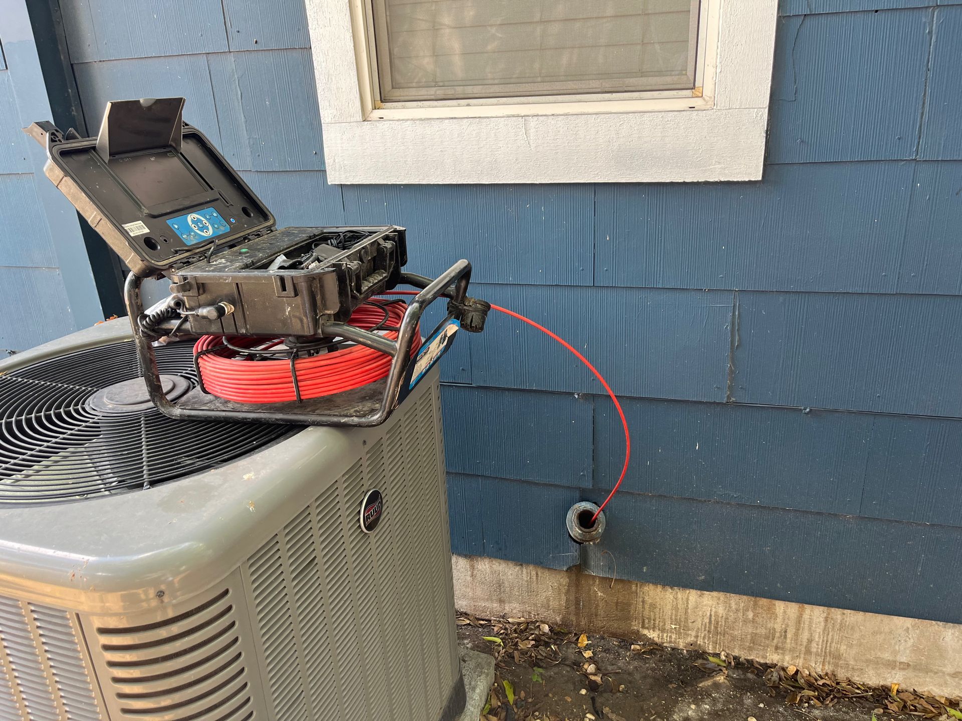 A camera is sitting on top of an air conditioner next to a window.