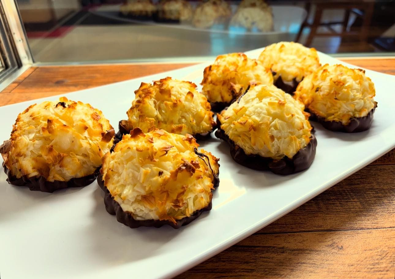 Coconut macaroons dipped in chocolate on a white rectangular plate.