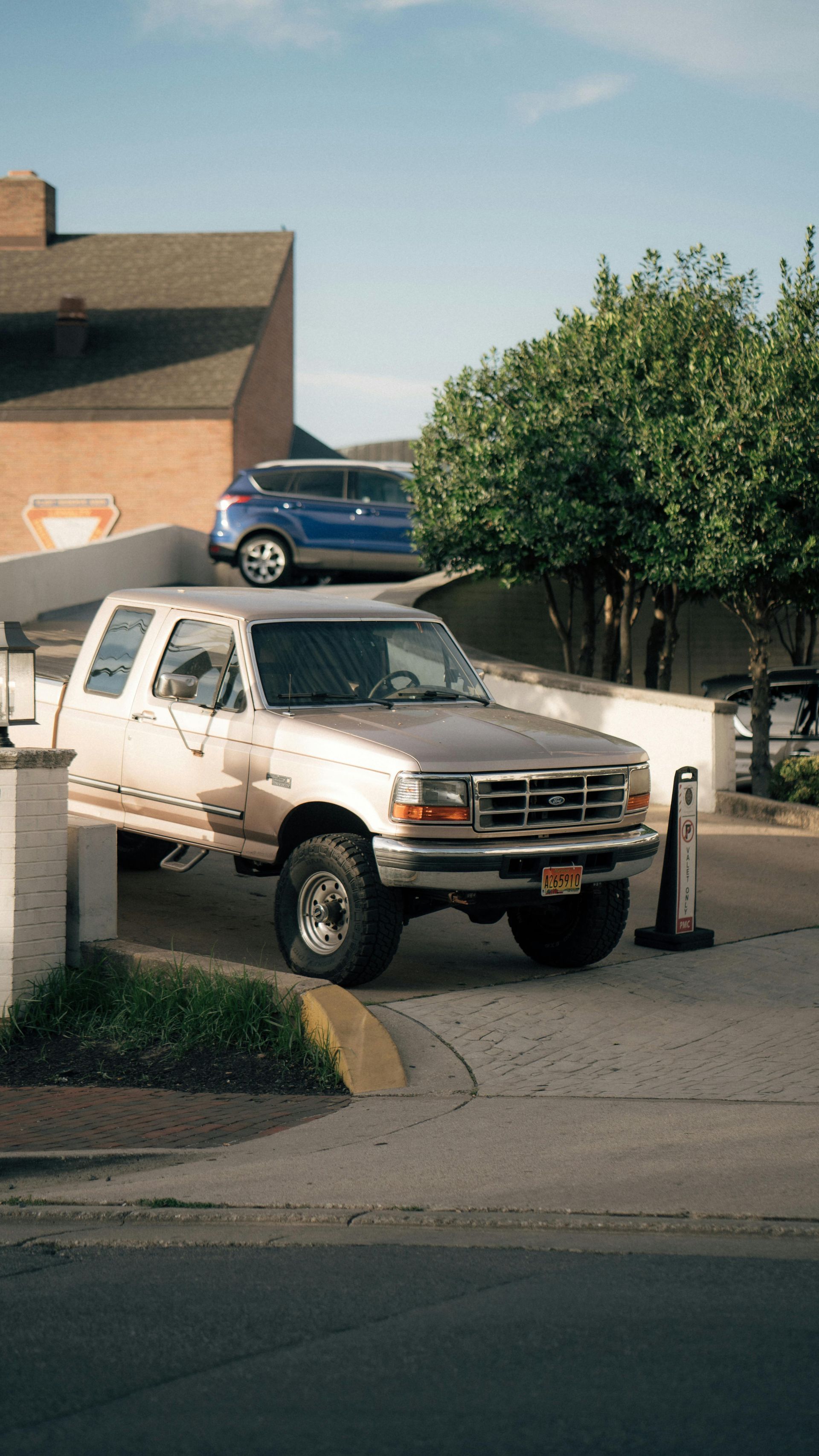 A white truck with the hood up is parked in a field