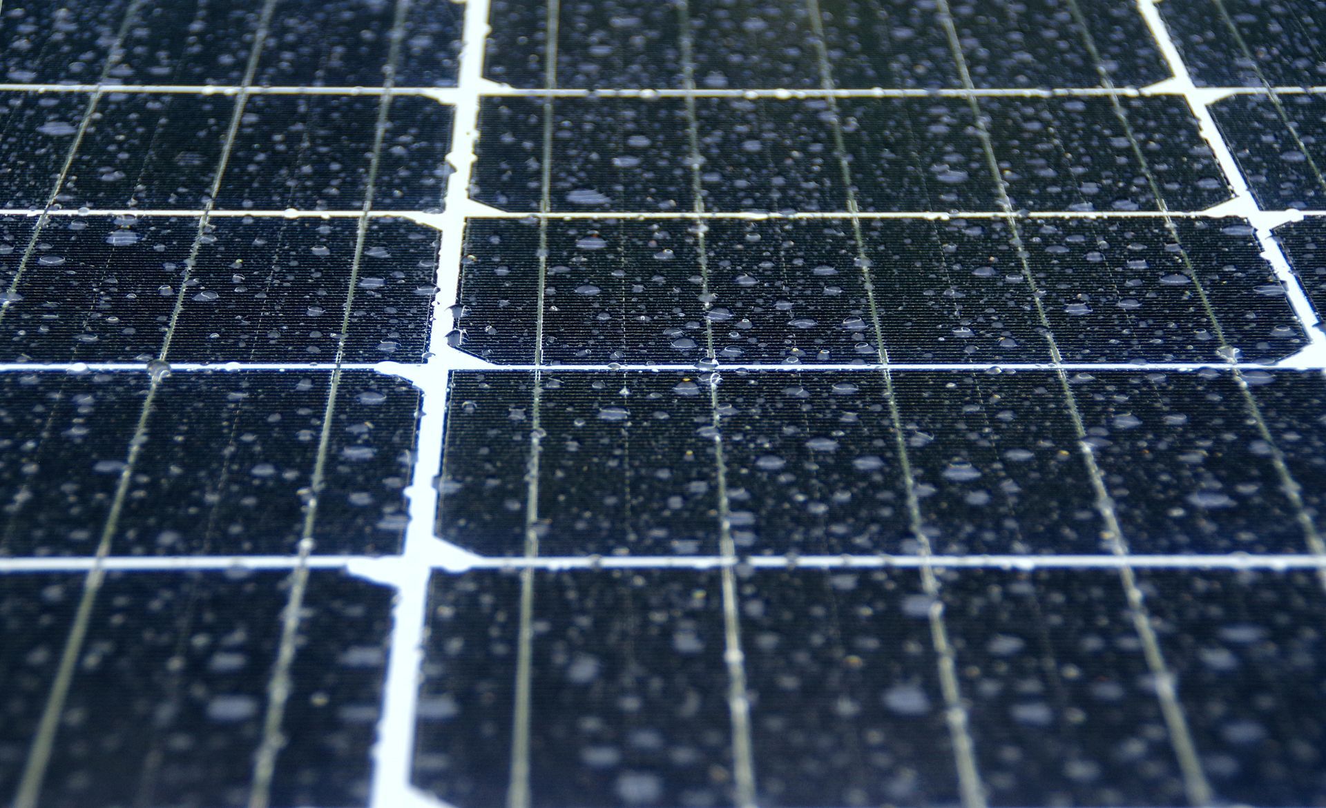 Una persona tiene in mano un tablet davanti a un tetto con pannelli solari.