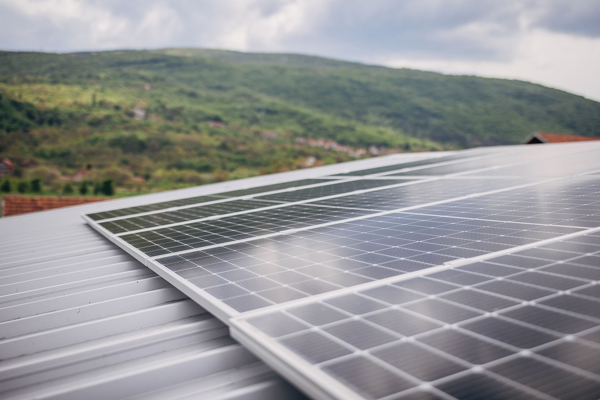Una fila di pannelli solari su un tetto con le montagne sullo sfondo.