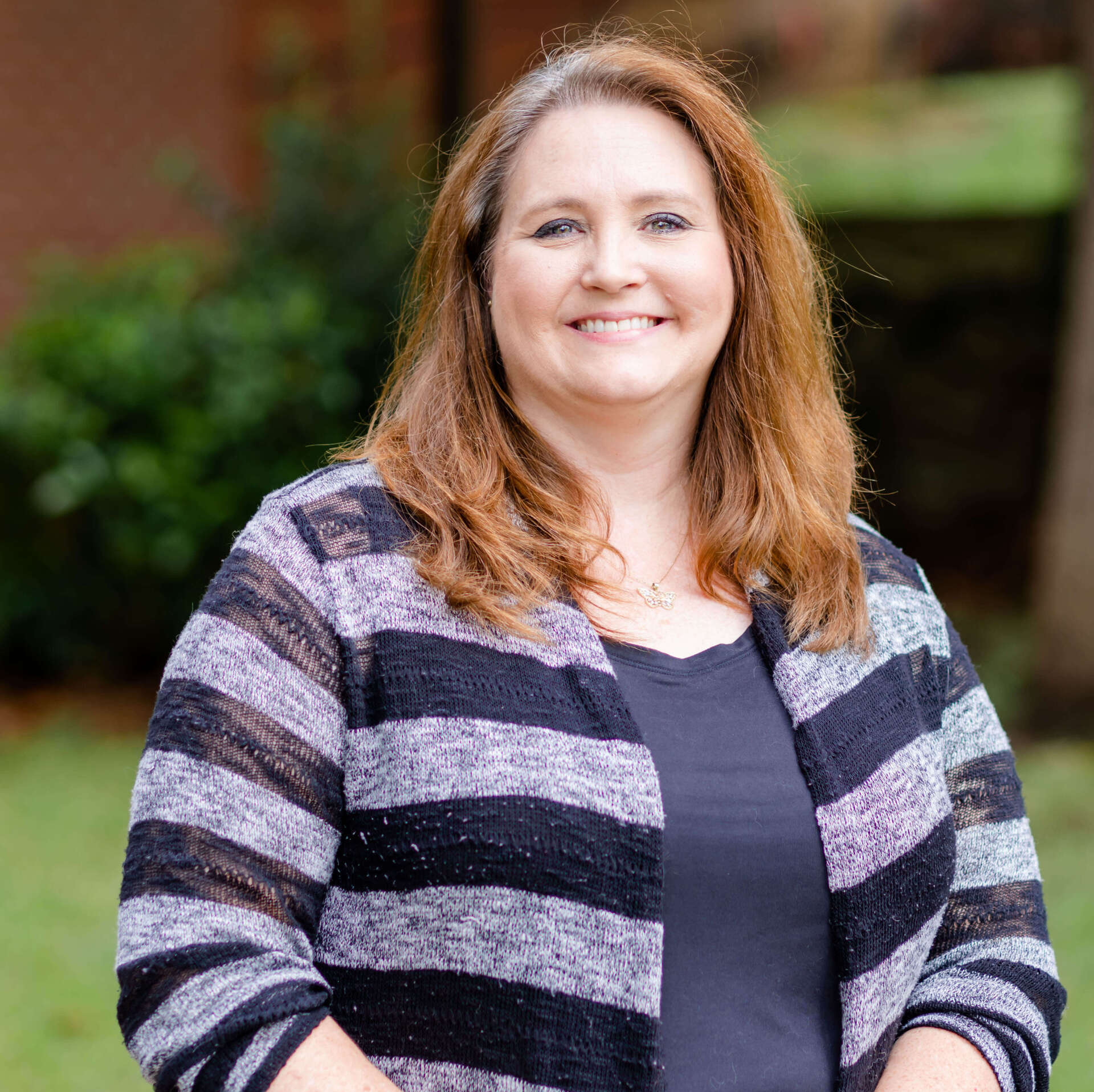 A woman wearing a striped sweater is smiling for the camera