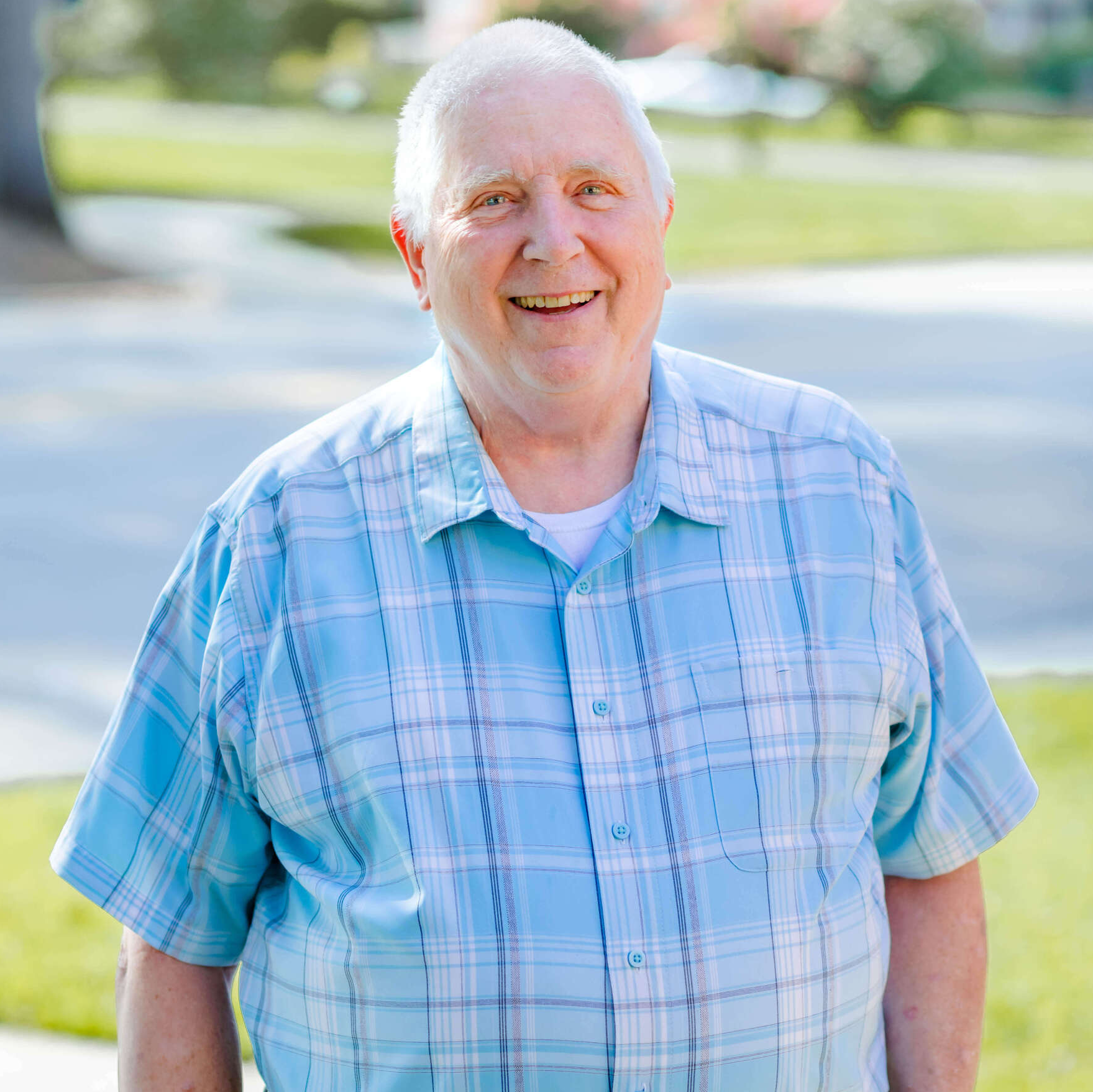 A man in a blue plaid shirt is smiling for the camera