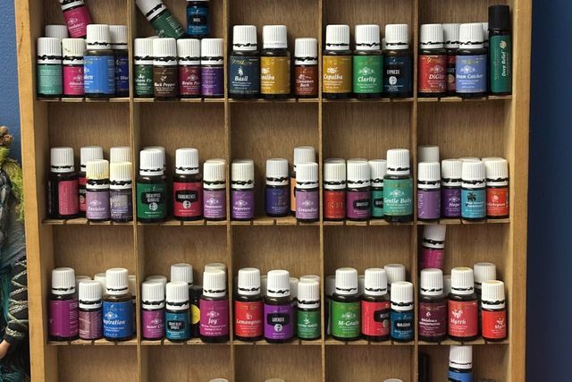 A wooden shelf filled with bottles of essential oils.