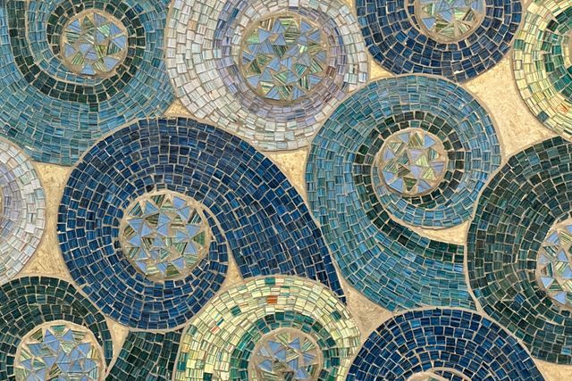 A close up of a mosaic of blue and green circles on a wall.