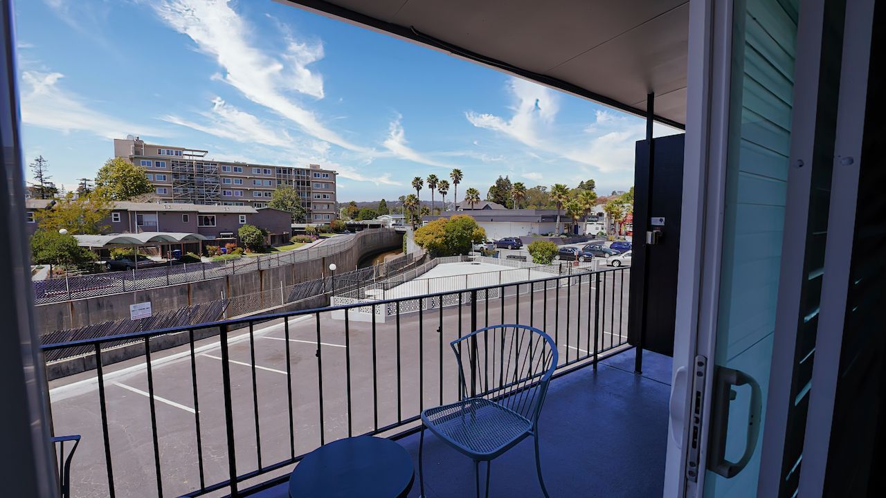 A balcony with a table and chairs and a view of a city.