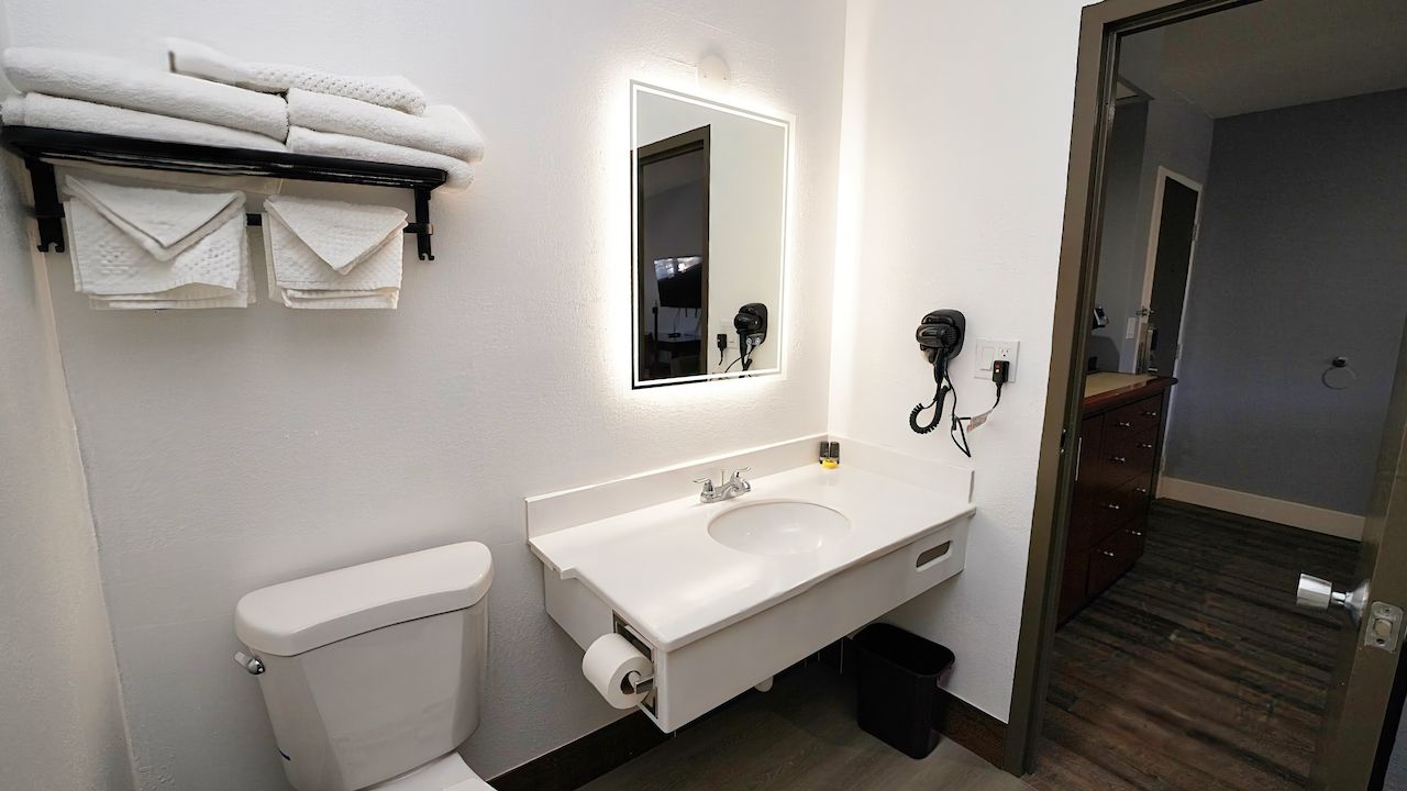 A bathroom with a toilet , sink , mirror and towels.
