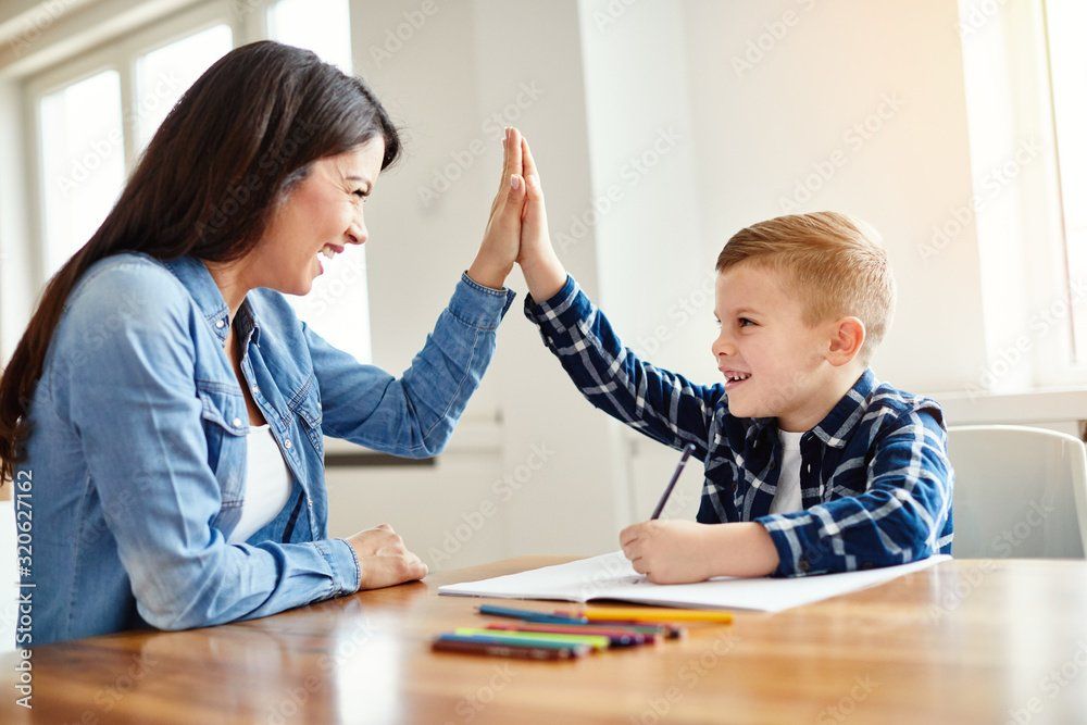 Mother and son high five. Working together on schoolwork.