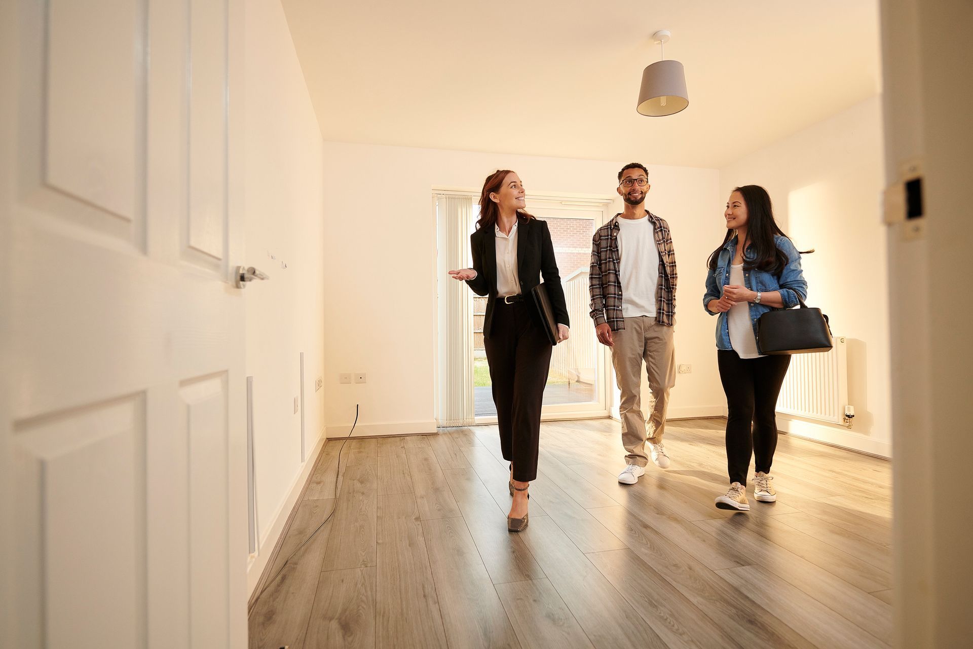 A woman is showing a man and a woman a room in a house.