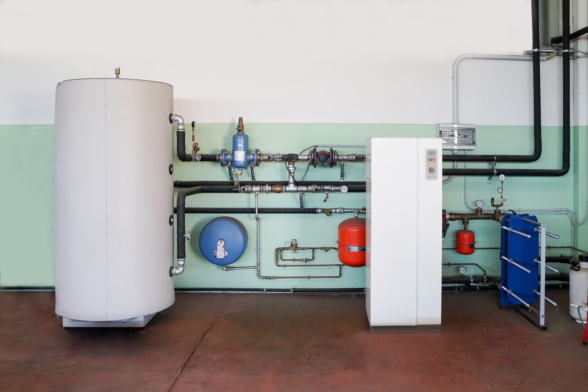 Interior geothermal heating system with tanks, pipes, and control units installed in a utility room. Interior geothermal heating system with tanks, pipes, and control units installed in a utility room.