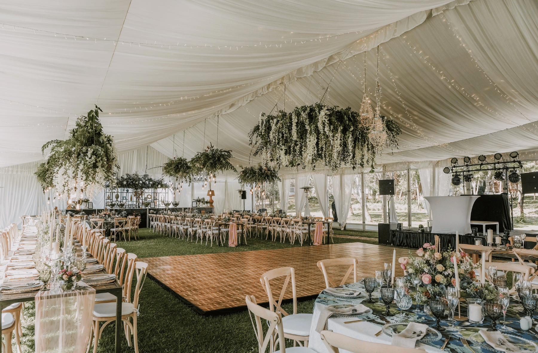 A large tent filled with tables and chairs and a dance floor.