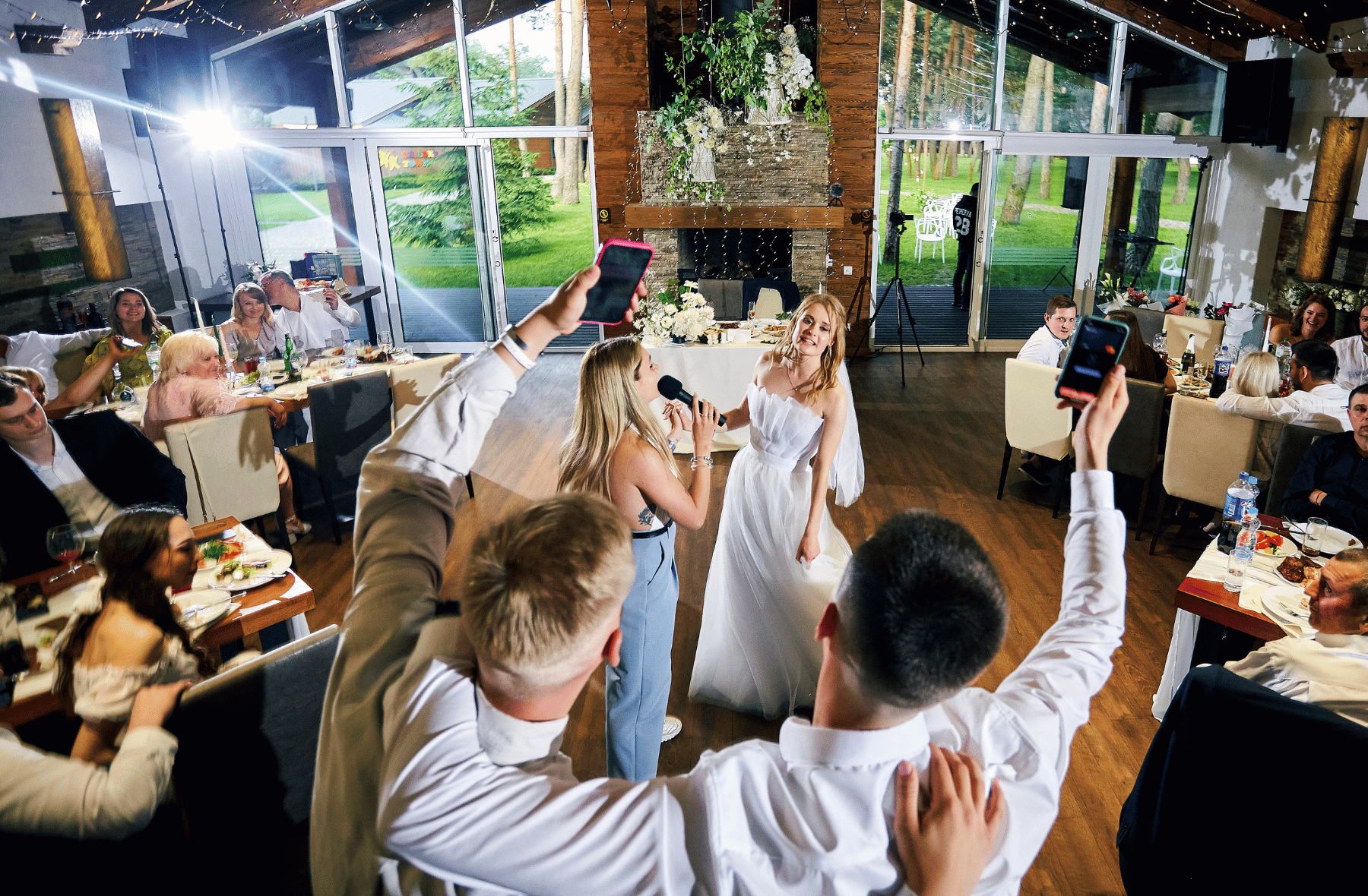 A bride and groom are singing into microphones at a wedding reception.