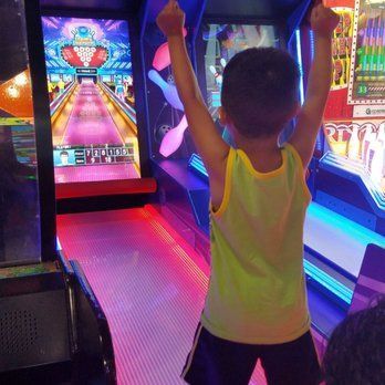 A young boy is playing a bowling game in an amusement park.