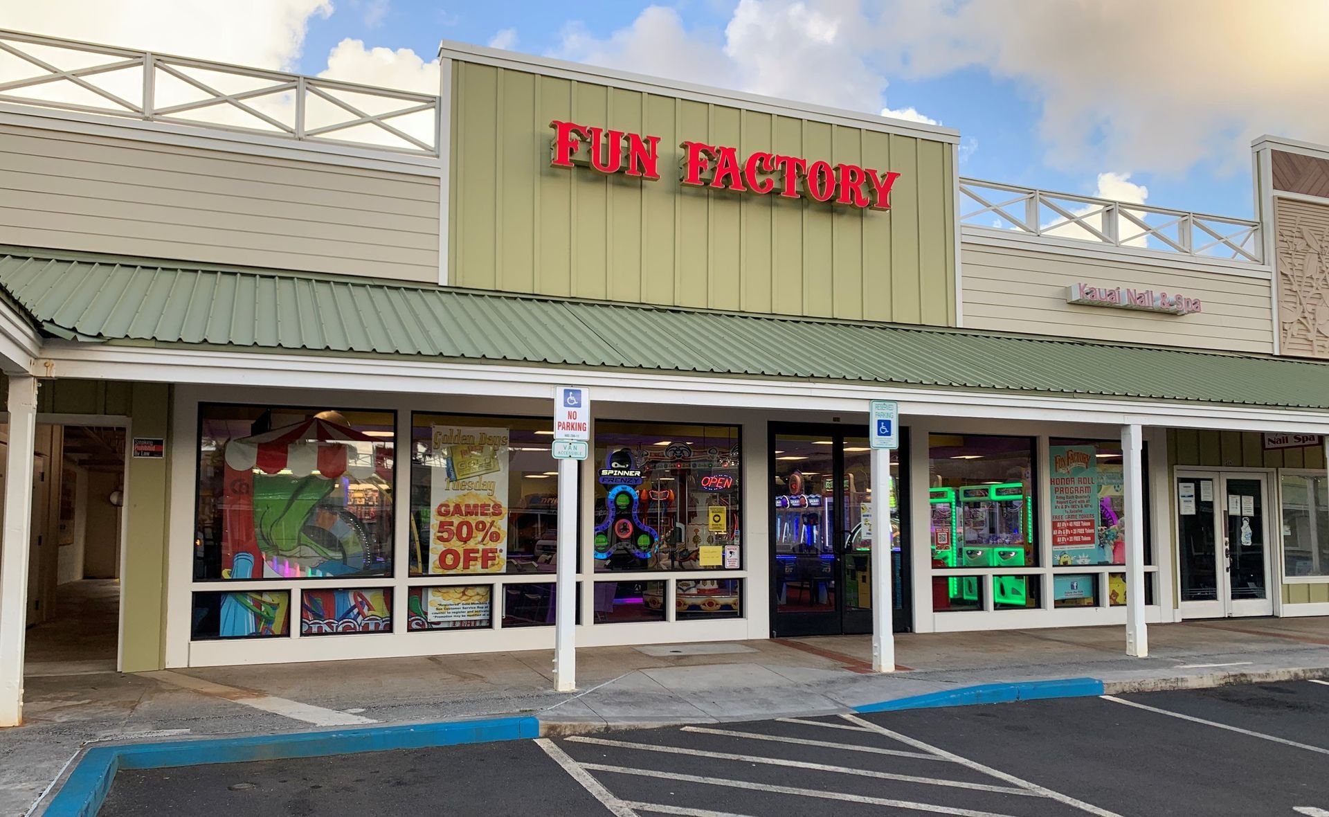 A store front with a green roof and a parking lot in front of it.