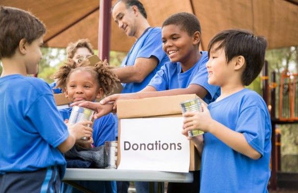 A group of children are holding a box of donations.
