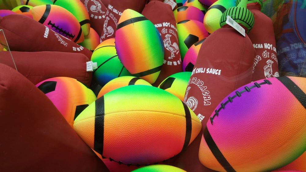 A bunch of colorful footballs are sitting on top of each other