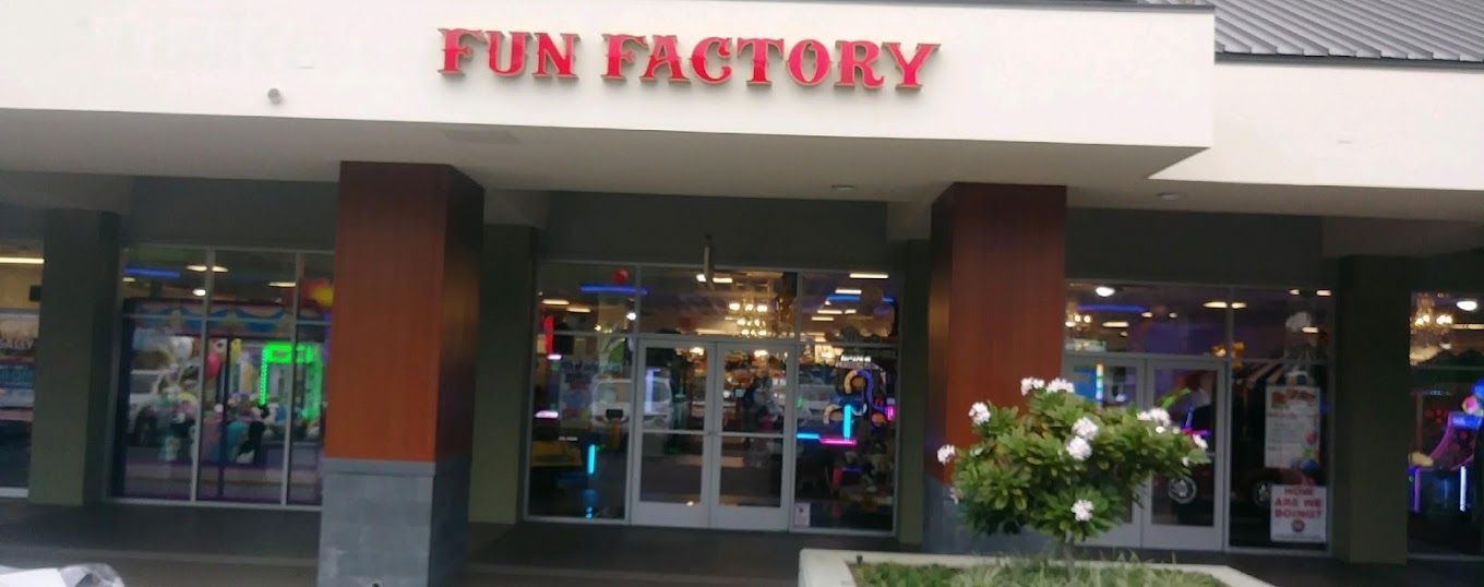 The front of a fun factory with a flower in front of it.