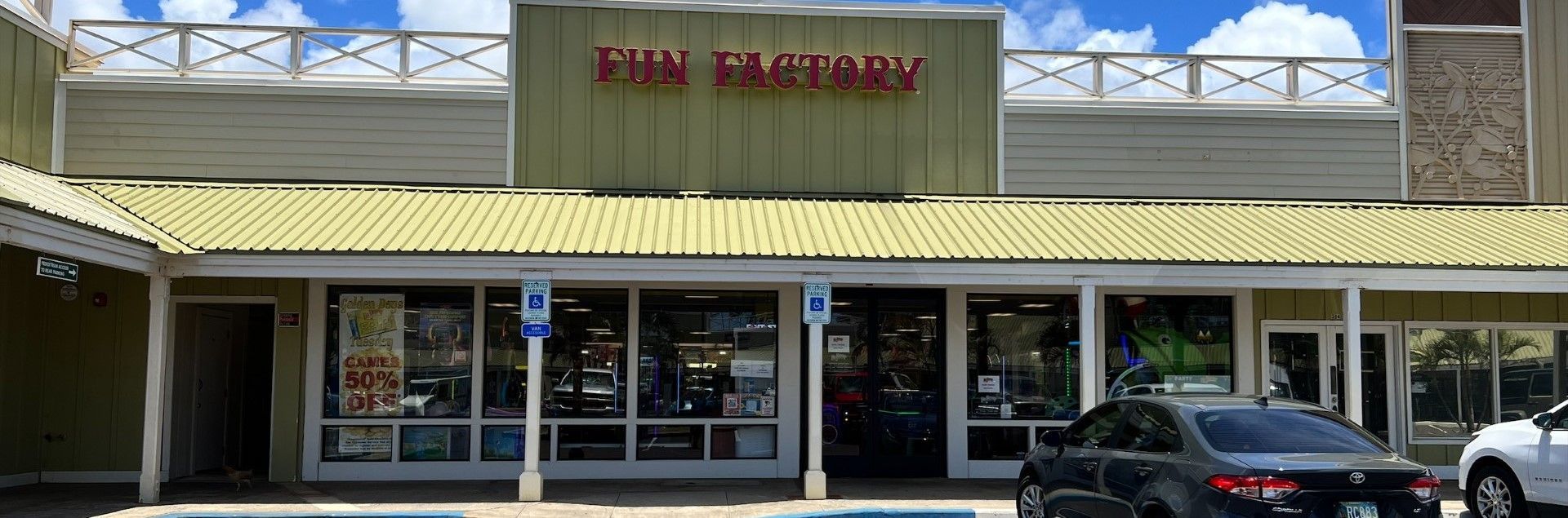 A car is parked in front of a store called fun factory.